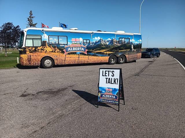The Let's Talk Alberta bus parked beside a “Let's Talk!” sandwich-board sign